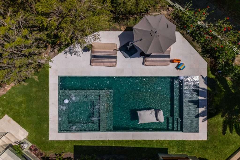 Kinvara Villa – Private Swimming Pool – Striking swimming pool surrounded by lawn, loungers and mature greenery, creating a secluded outdoor retreat.
