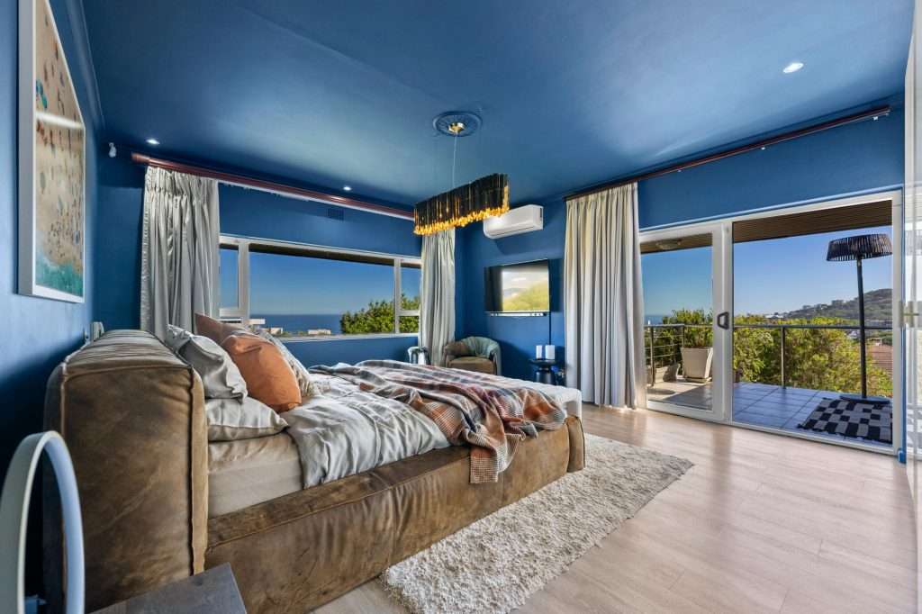 Kinvara Villa – Blue Bedroom with Ocean Views – Dramatic blue bedroom with ocean views and glass doors opening onto a private furnished balcony.