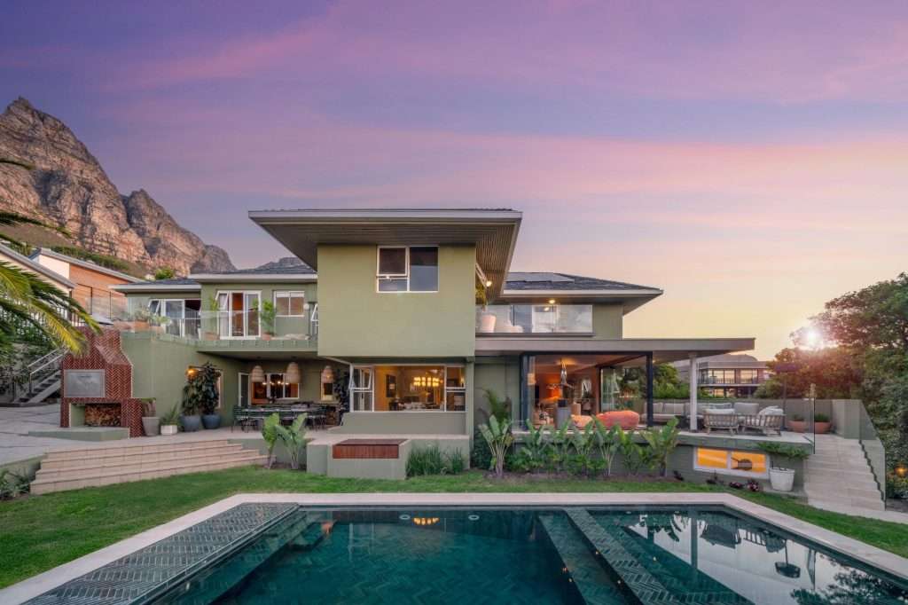 Kinvara Villa – Poolside at Sunset – Beautiful exterior view of the villa and private pool at dusk, capturing the home’s relaxed indoor-outdoor lifestyle beneath the slopes of Lion’s Head.
