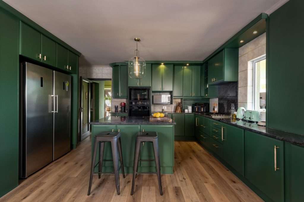 Kinvara Villa – Designer Kitchen – Striking green kitchen with a central island, generous cabinetry, integrated appliances and breakfast-bar seating.